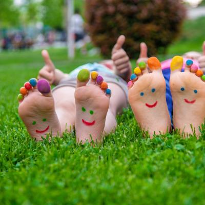 hildren's feet with a pattern of paints smile on the green grass