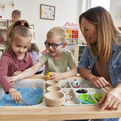 Mother playing on sensory table with two young children