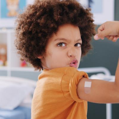 Young boy proudly lifts arm after receiving vaccine