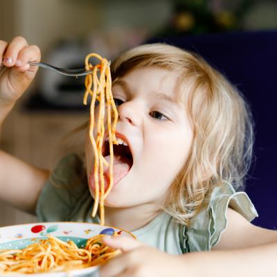 Young girl eating spaghetti happily
