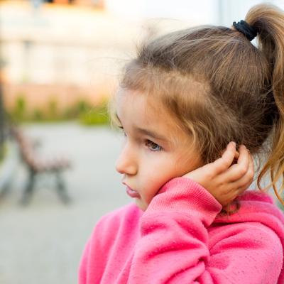 Young girl, around 3, clutching left ear
