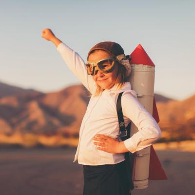 Child with pilot goggles on and a rocket backpack. 