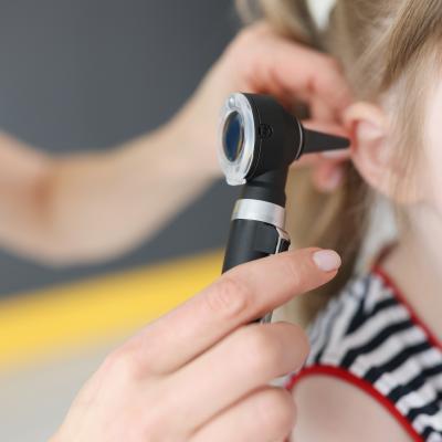 Close-up of child getting ear examined with otoscope 