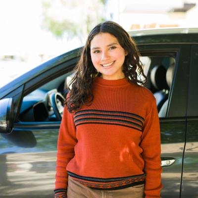 Teen driver standing in front of car