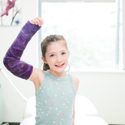 A patient with a cast in orthopedics clinic looks into the camera.