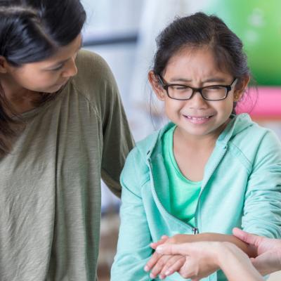 Child with wrist injury next to two adults