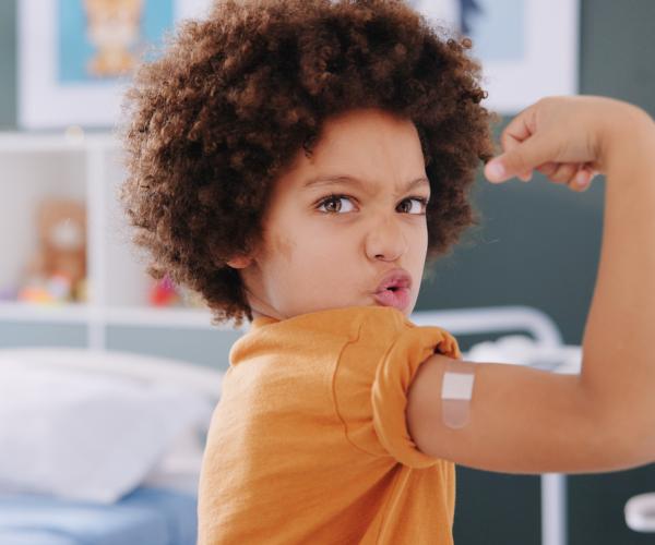 Young boy proudly lifts arm after receiving vaccine