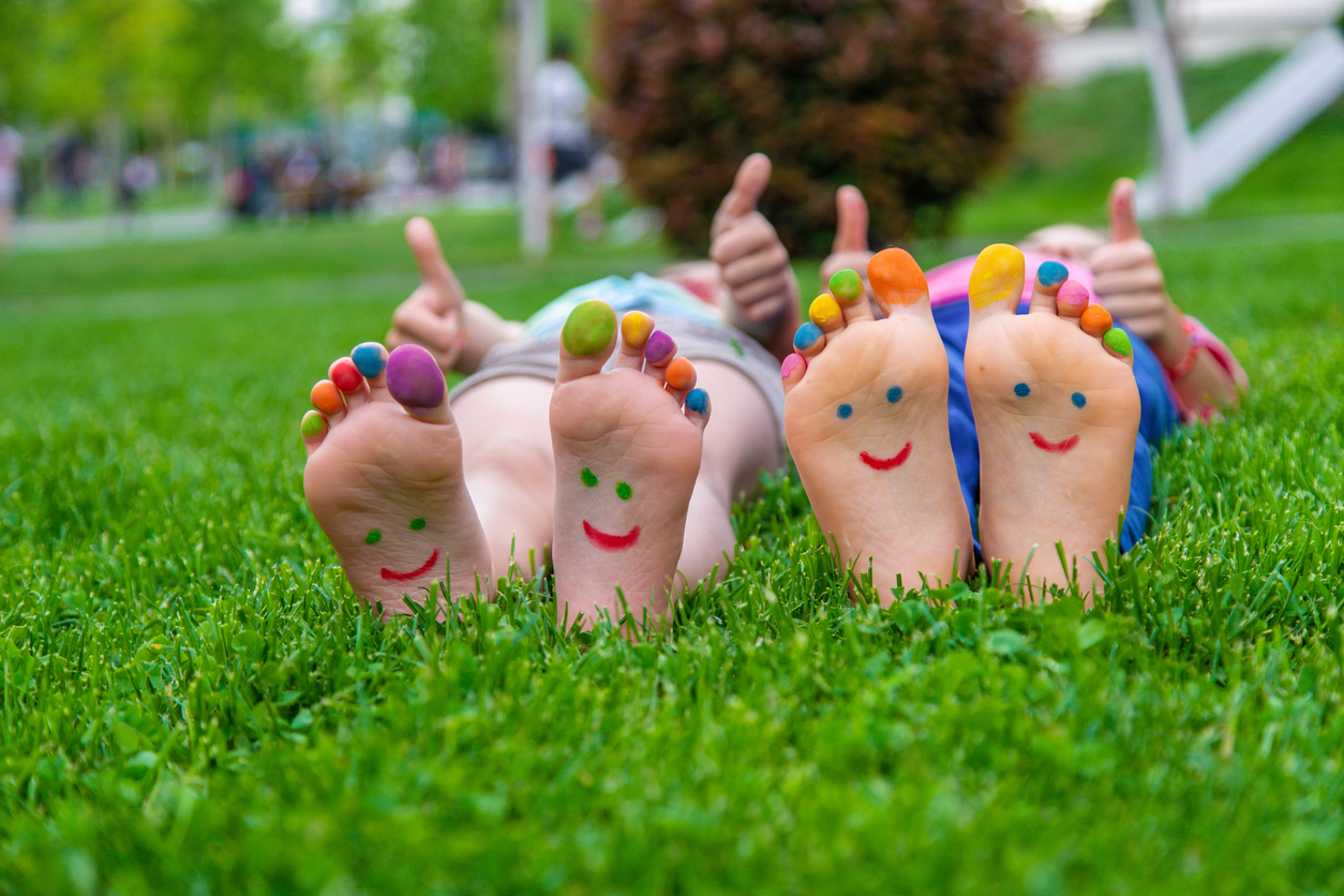 hildren's feet with a pattern of paints smile on the green grass