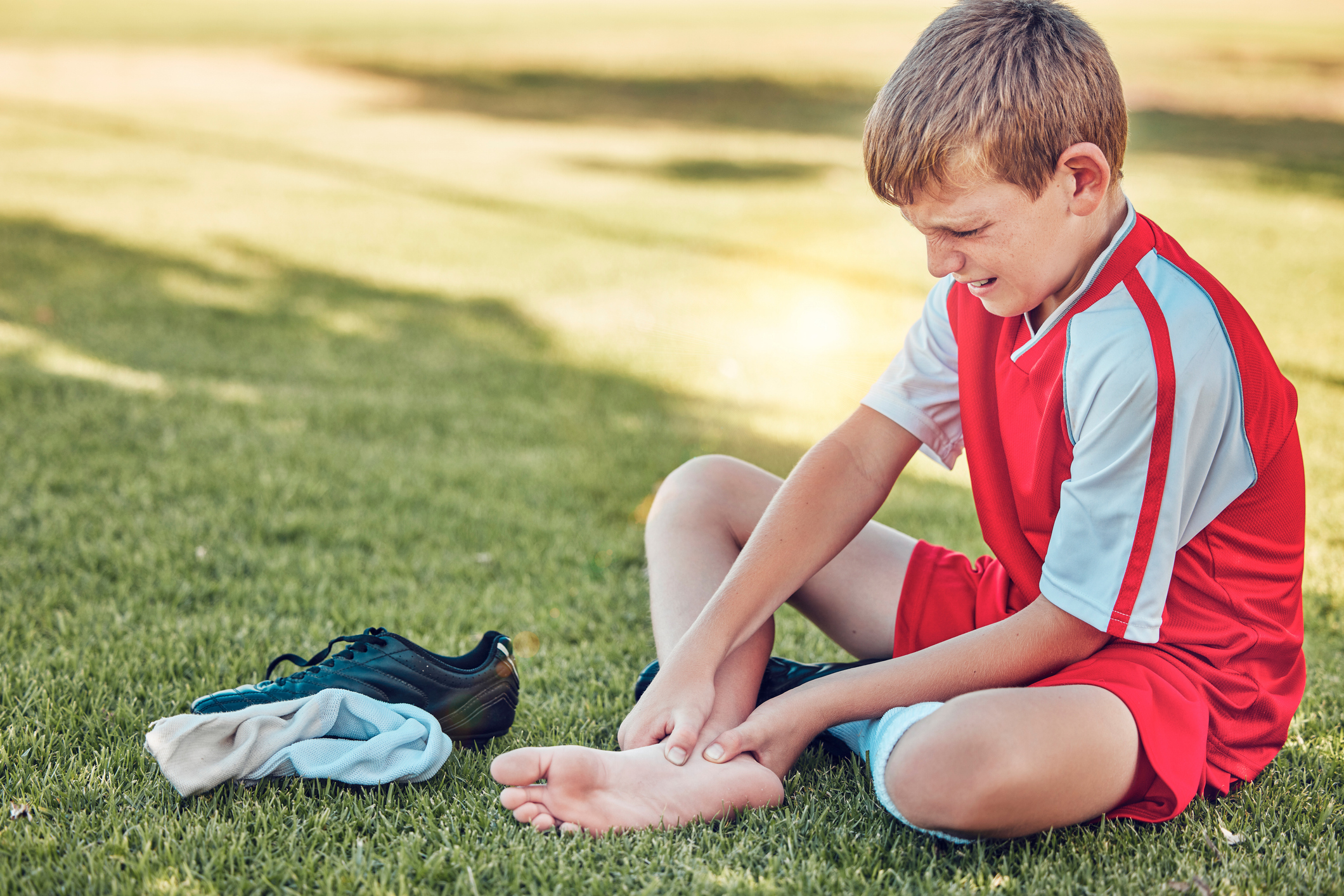 young soccer player with heel pain on field