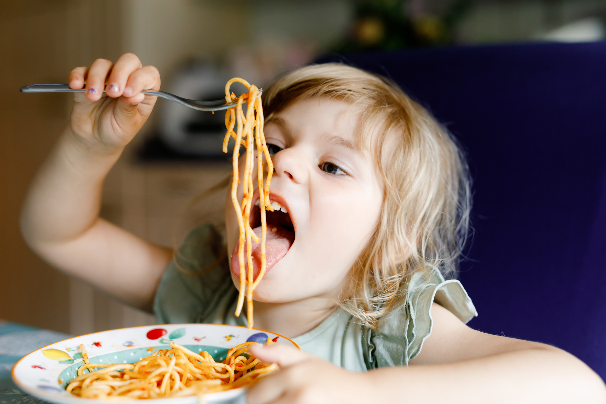 Young girl eating spaghetti happily
