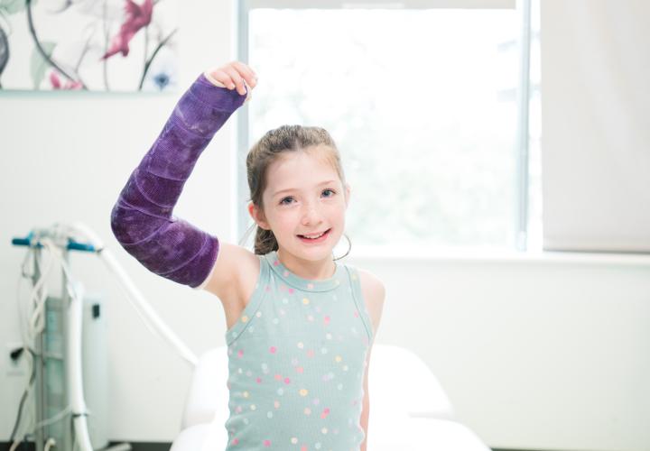 A patient with a cast in orthopedics clinic looks into the camera.